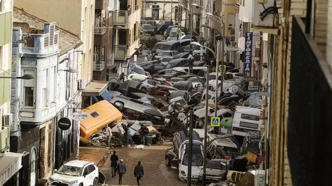 Una imatge d'un carrer de Picanya plena de cotxes arrossegats pel temporal d'aigua